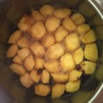 Apples stew in a steel pot during fruit compote preparation.