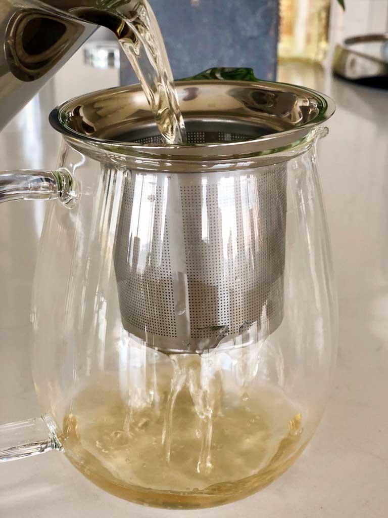 Sukku coffee is poured from the pot, through a strainer, and into a glass pot.