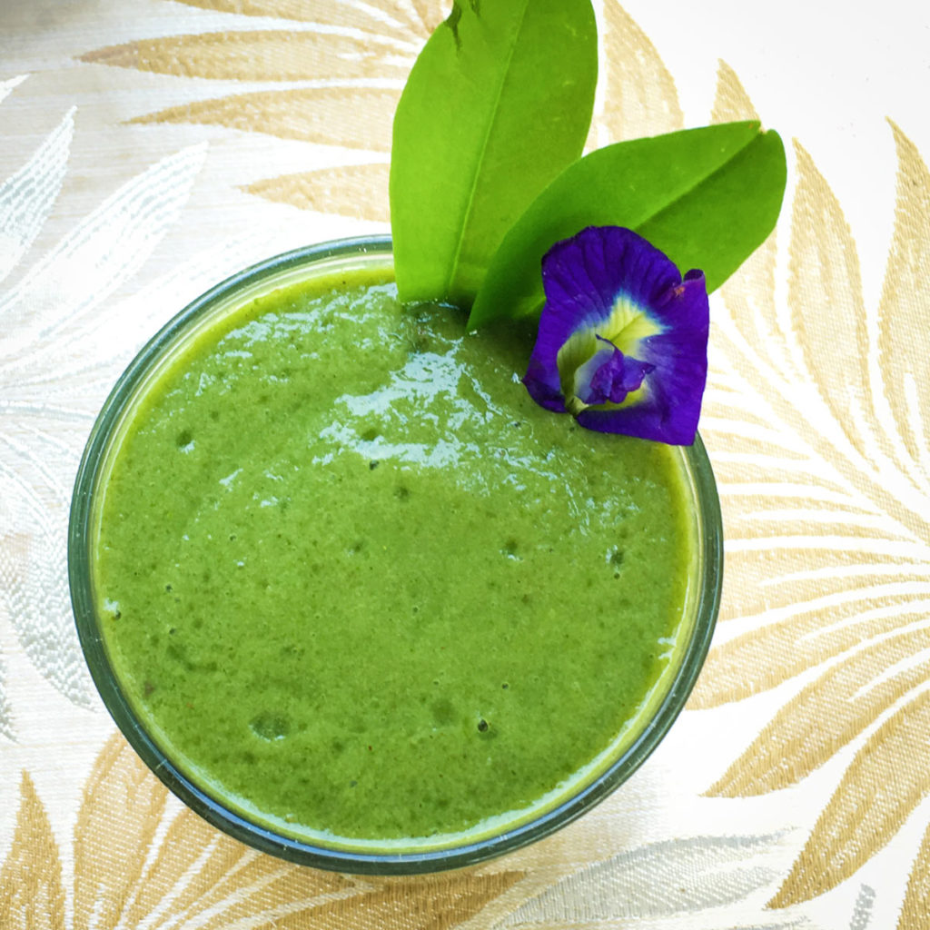 A green and minty smoothie with a purple flower garnish