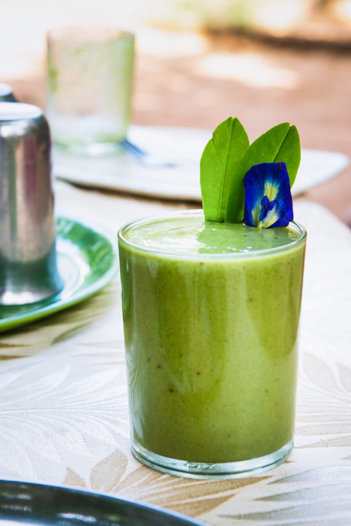 A green and minty smoothie with a purple flower garnish