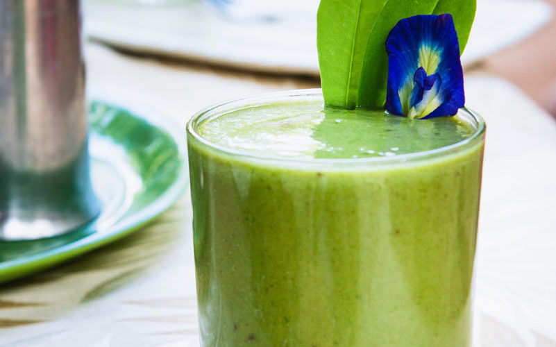 A green and minty smoothie with a purple flower garnish