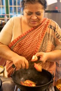 Abida Rasheed cuts tomato into a wok.