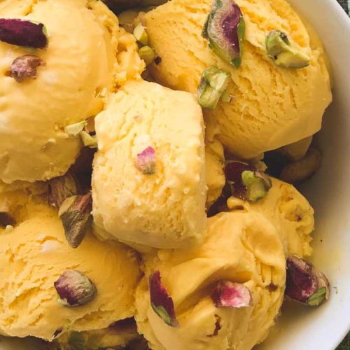 Orange coloured Mango Ice Cream sits in a bowl.