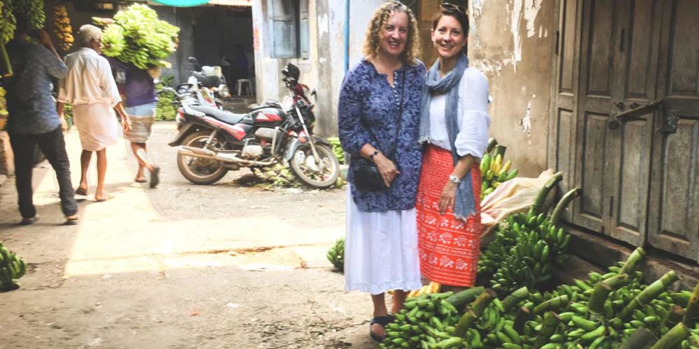 Pauli-Ann and Karen standing near bananas in Kozhikode (Calicut)