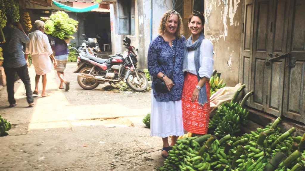 Pauli-Ann and Karen standing near bananas in Kozhikode (Calicut)