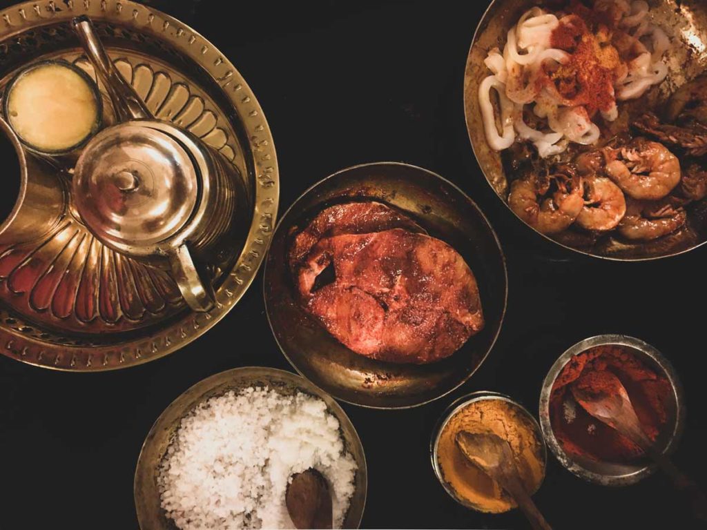 Raw fish steak and Moplah spices in bowls.