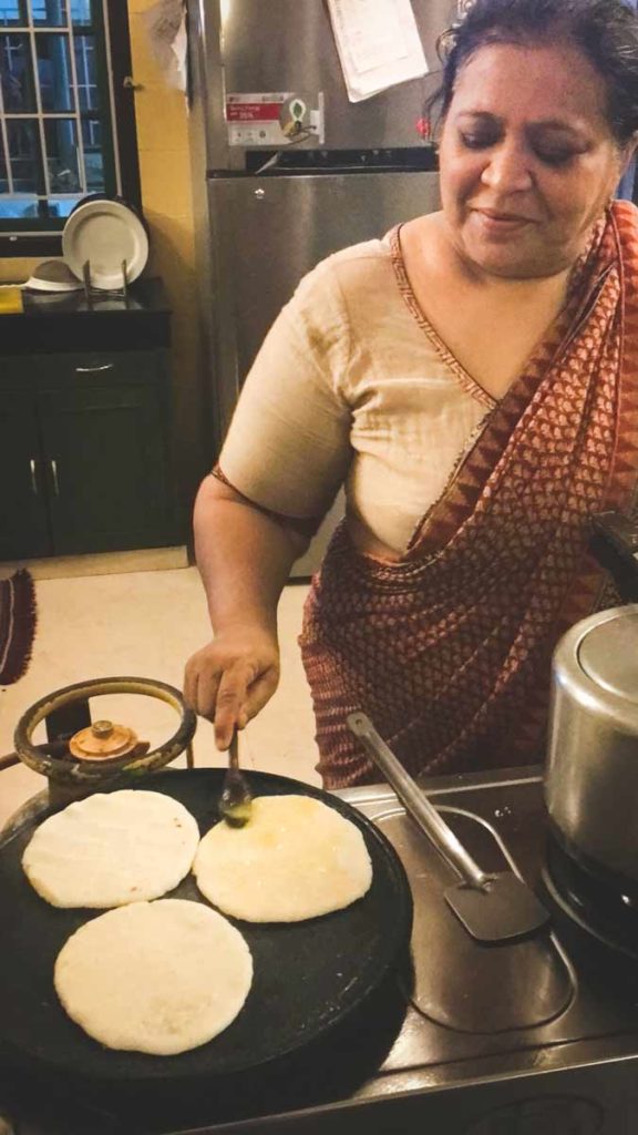 Three flat pathiri breads sit on a cast iron grill.