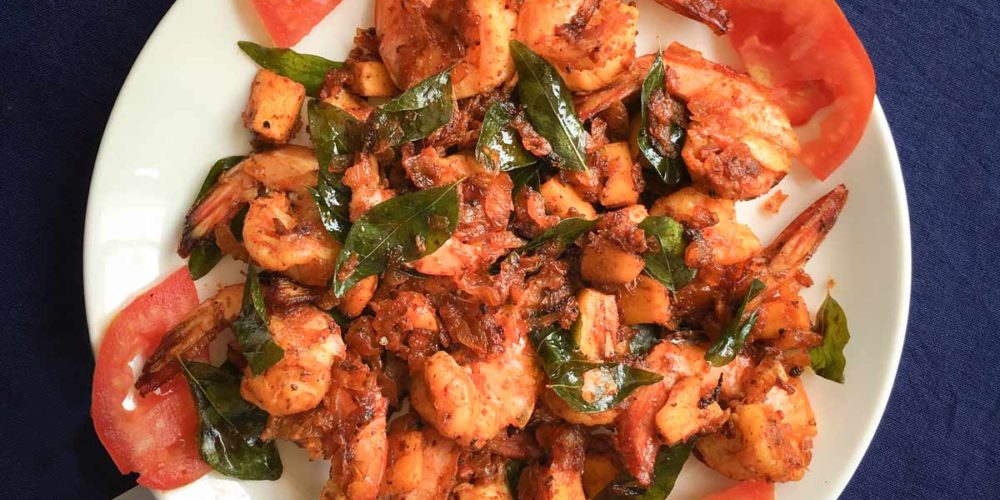 A dish of coconut prawns sits on a blue tablecloth