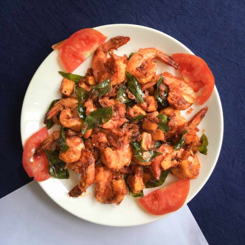 A dish of coconut prawns sits on a blue tablecloth