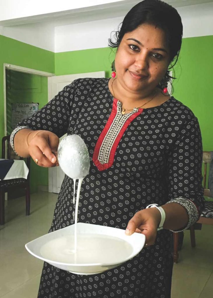 Appam batter falling from a ladle.