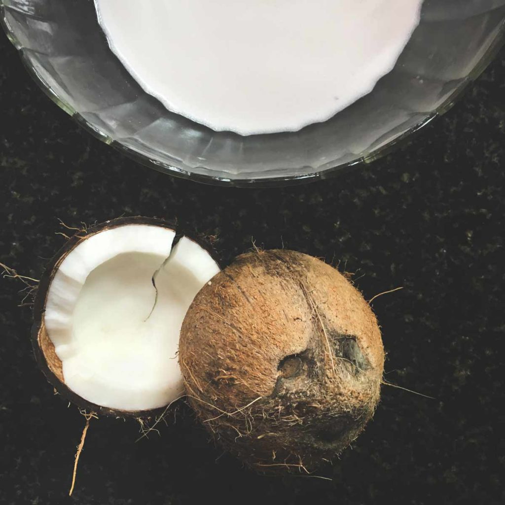 Split coconut and a bowl of coconut milk