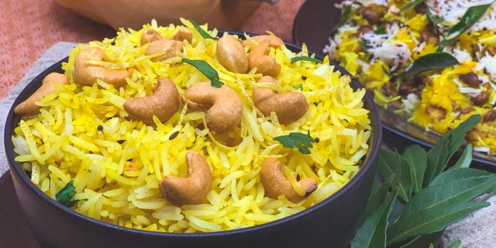 Yellow coloured lemon rice topped with whole cashews.