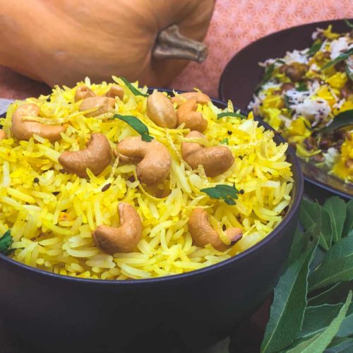 Yellow coloured lemon rice topped with whole cashews.