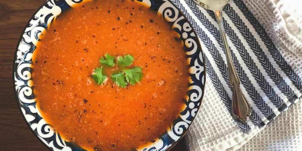 Bright red tomato soup with a green cilantro garnish.