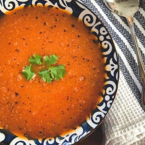 Bright red tomato soup with a green cilantro garnish.