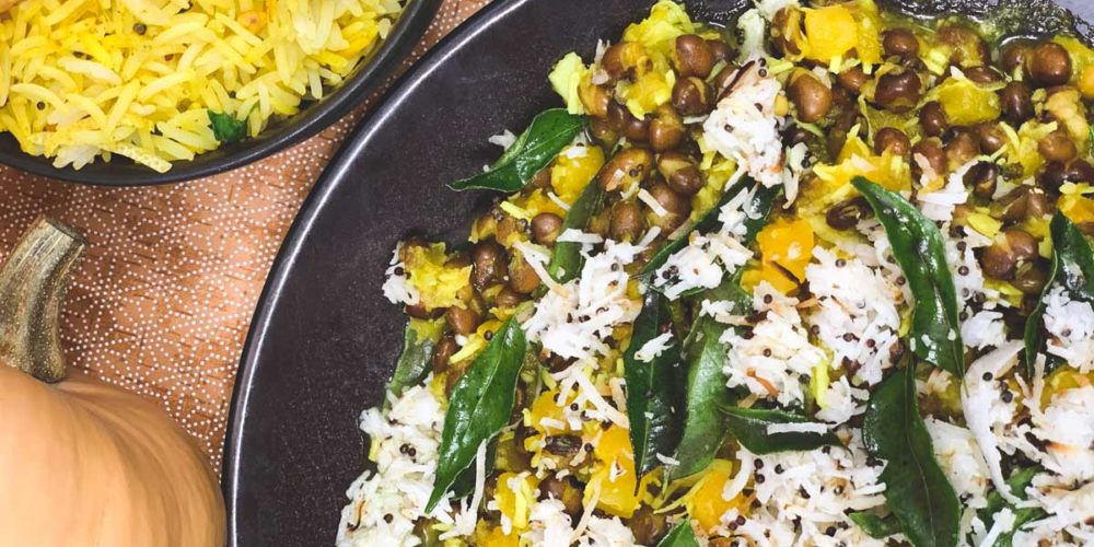 Pumpkin and Pigeon Peas with rice and curry leaves sit in a black serving bowl.