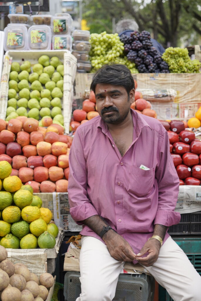 man in purple shirt in front of fruite